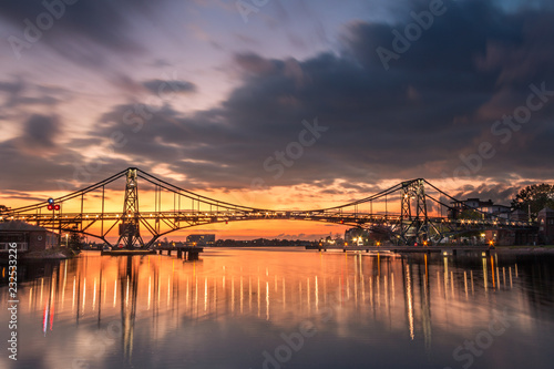 Dramatischer Sonnuntergang hinter einer Brücke am Wasser photo