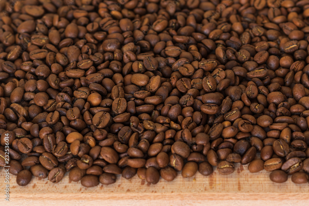 Fototapeta premium Closeup of fragrant roasted coffee beans on a wooden board. Selective focus. place for text.