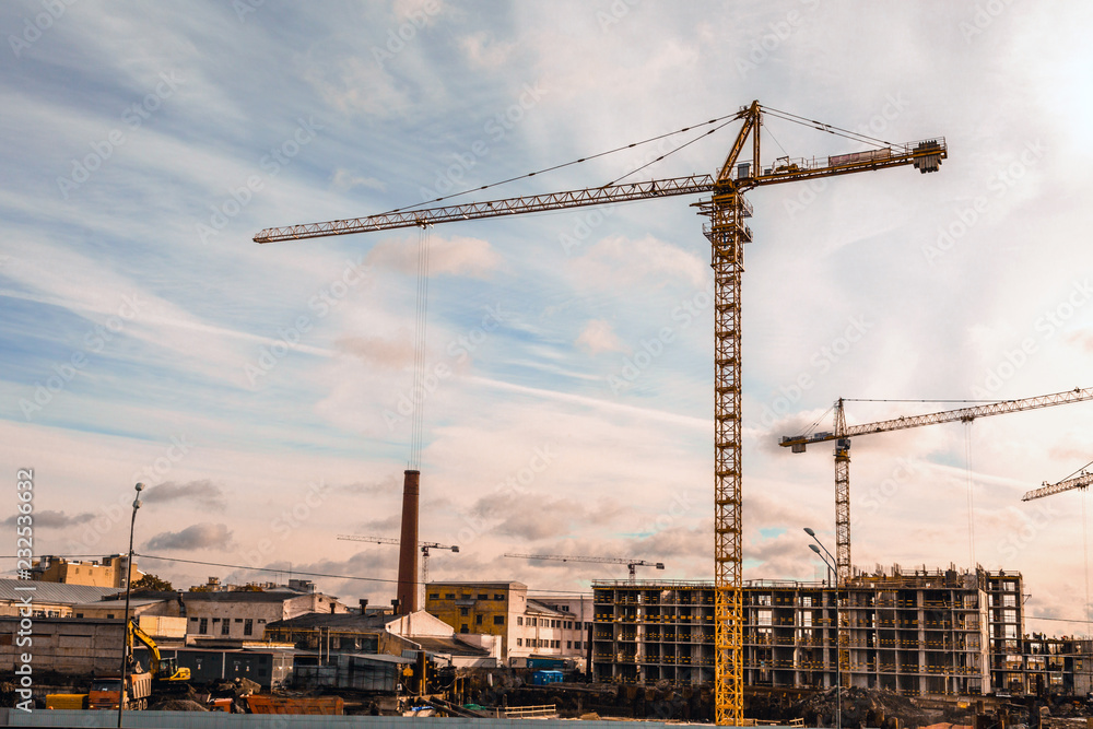 construction of residential apartments with high-rise cranes at sunset construction of residential apartments with high-rise cranes at sunset