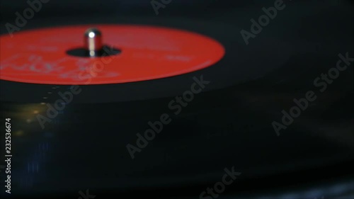 A needle is put down on the spinning black vinyl record on the turntable photo