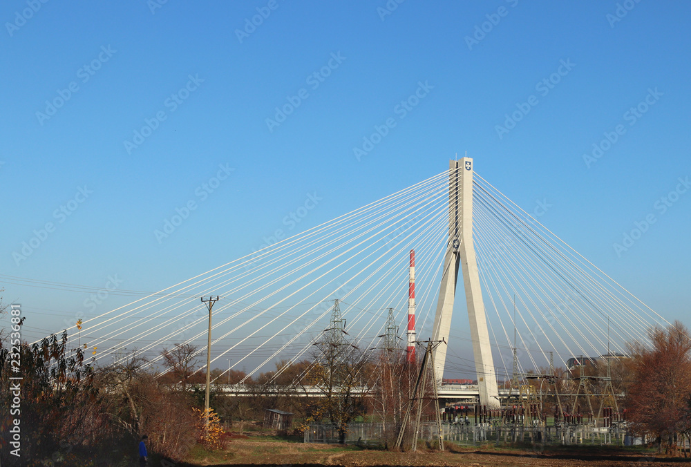 Fototapeta premium Rzeszow, Poland - 9 9 2018: Suspended road bridge across the Wislok River. Metal construction technological structure. Modern architecture. A white cross on a blue background is a symbol of the city.