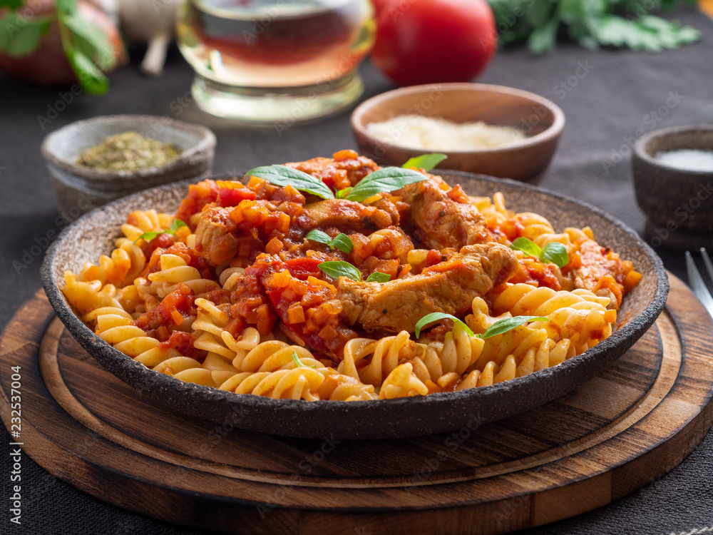 fusilli pasta with tomato sauce, chicken fillet with basil leaves on