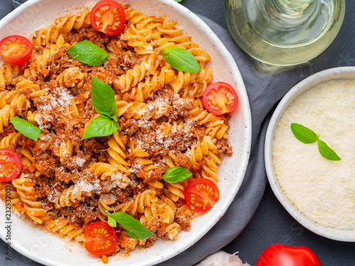 Bolognese pasta. Fusilli with tomato sauce, ground minced beef, basil leaves. Traditional italian cuisine. Top view, close up