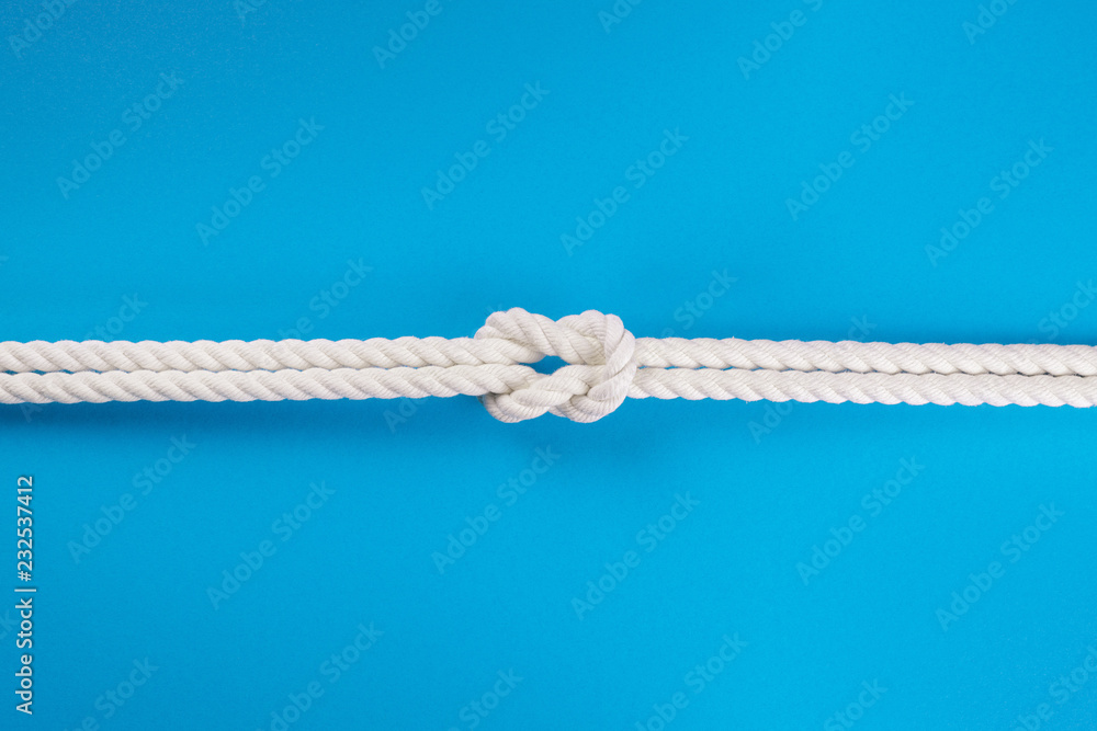 White ship ropes connected by reef knot on blue