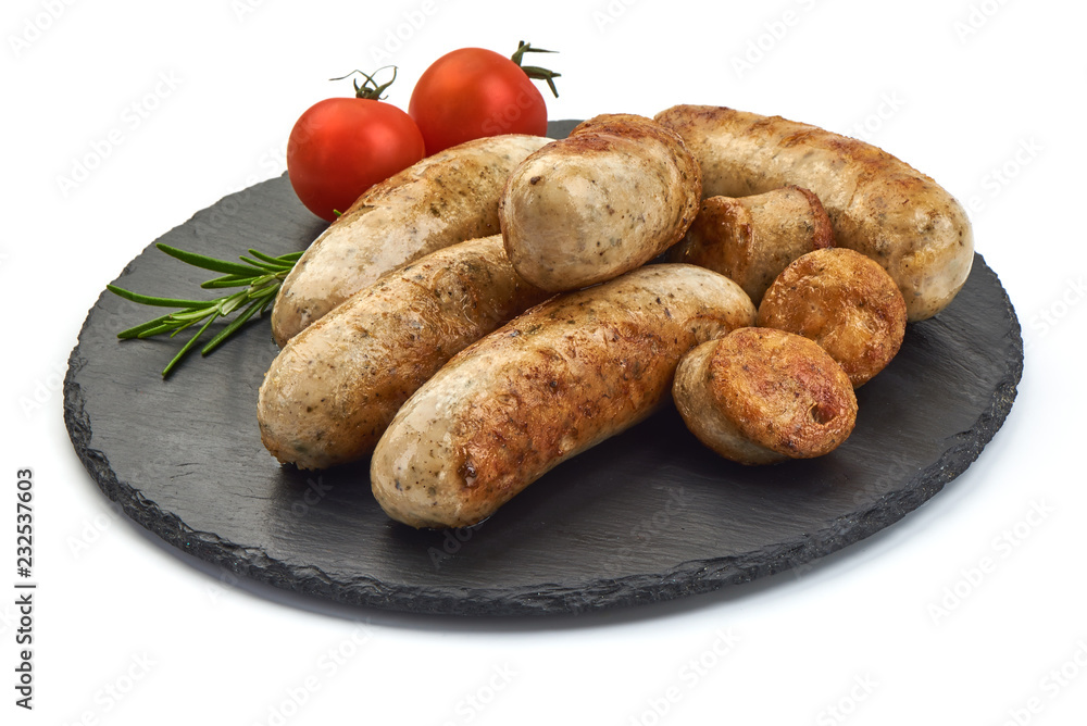 Hot German Bratwurst with herbs and tomatoes on a shale slate plate, isolated on a white background. Close-up. Hot German Bratwurst with herbs and tomatoes on a shale slate plate, isolated on a white background. Close-up.