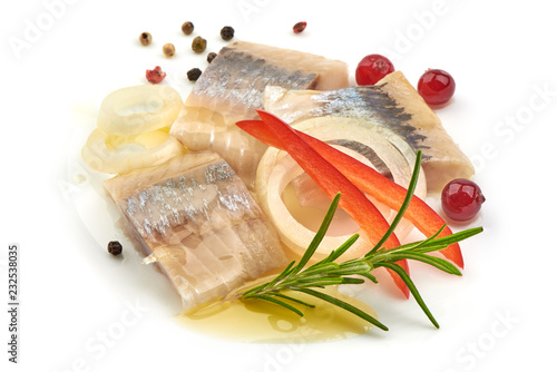 Pieces of salted herring fillet with onion ring, pepper and herbs, isolated on a white background