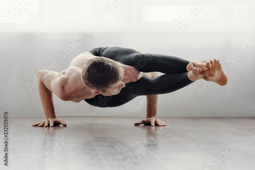 Fotografia Fit muscular flexible man posing in difficult yoga pose