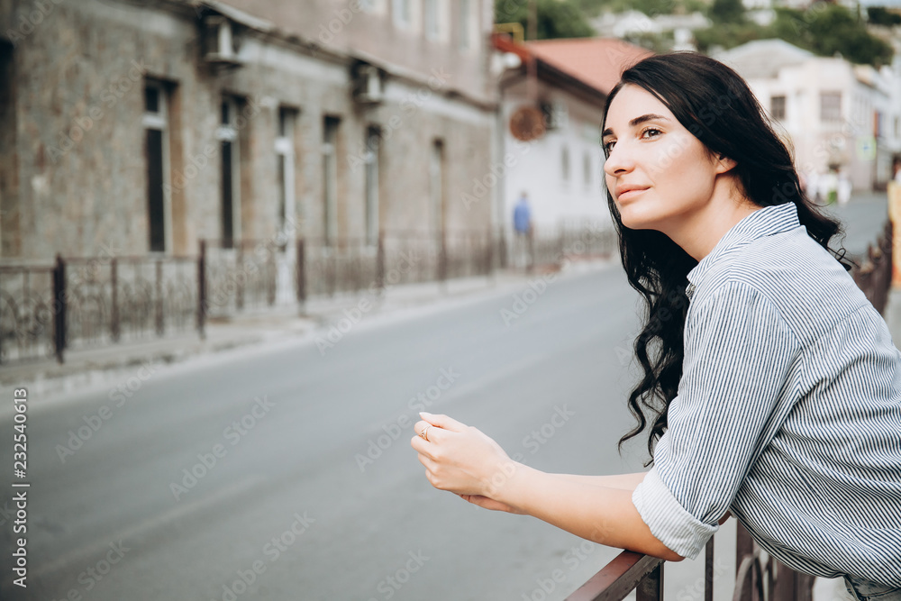 Fototapeta premium beautiful woman standing by rail at the street and looking around. portrait