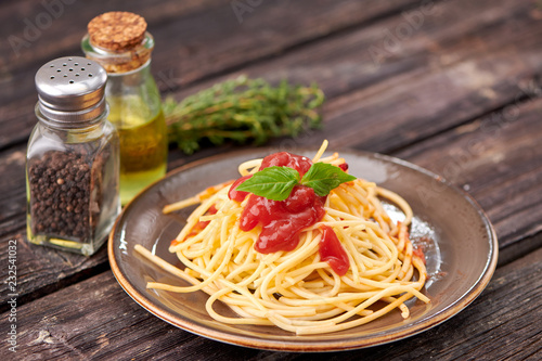 spaghetti with ketchup and Basil on dark wooden background