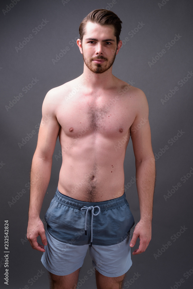Young handsome bearded man shirtless against gray background Young handsome bearded man shirtless against gray background