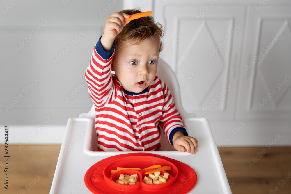 Toddler in high chair playing with finger food Toddler in high chair playing with finger food
