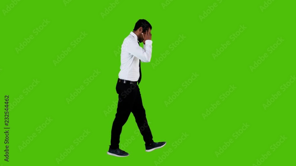 Sad and depressed businessman walking upset over a green background. Full side shot. Sad and depressed businessman walking upset over a green background. Full side shot.