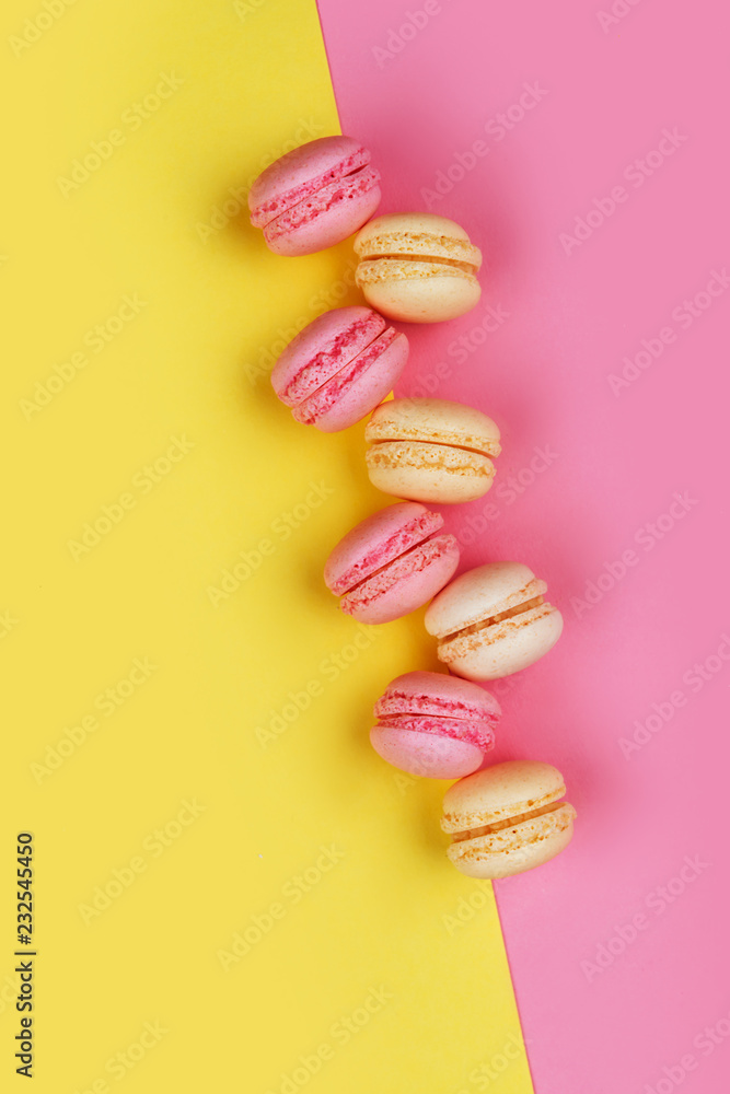 Tasty macarons on yellow - pink background divided diagonally into two triangles Tasty macarons on yellow - pink background divided diagonally into two triangles
