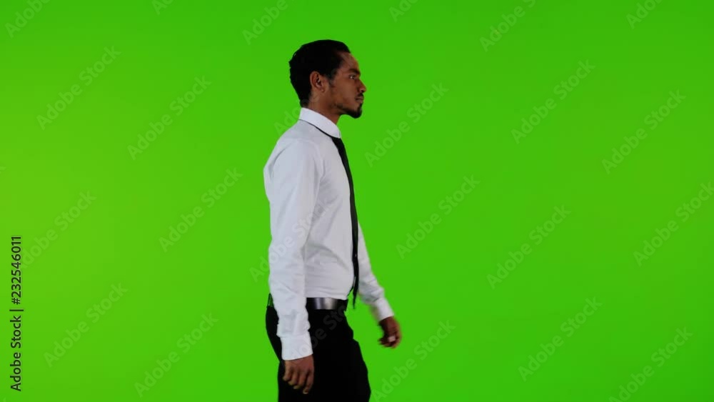 Sad ill and depressed businessman walking upset over a green background. Medium side shot. Sad ill and depressed businessman walking upset over a green background. Medium side shot.