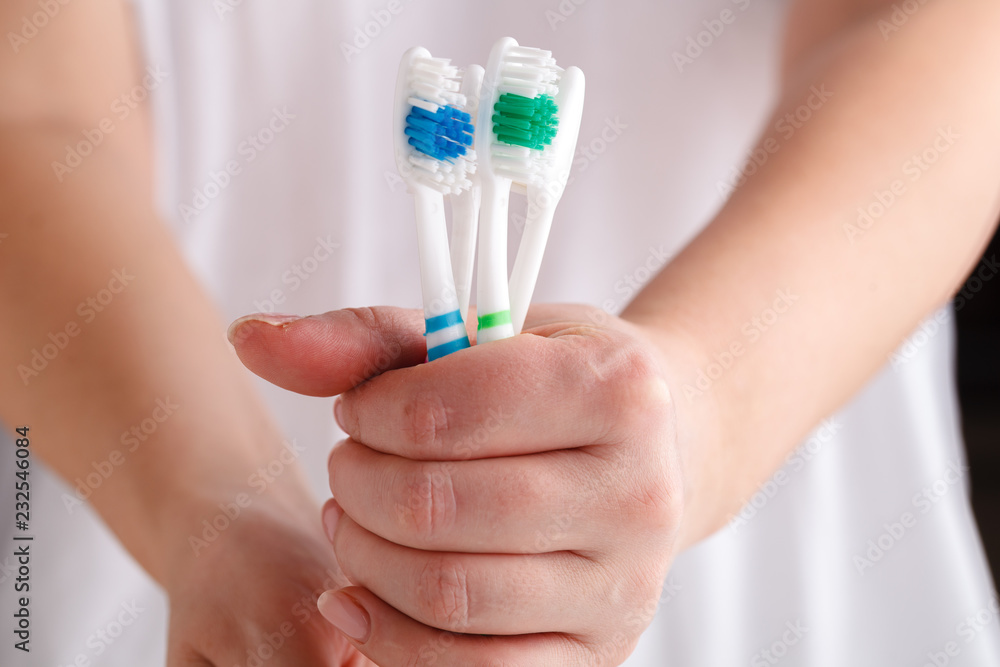 hand holding four toothbrushes of different colors hand holding four toothbrushes of different colors