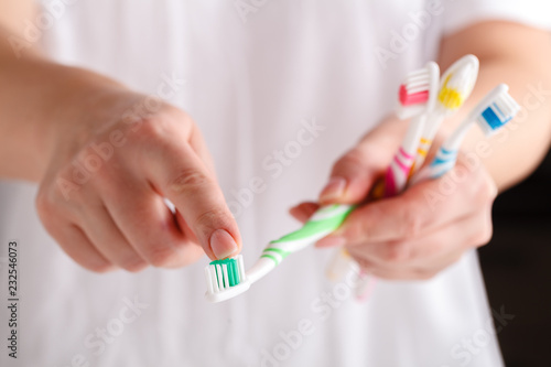 hand holding four toothbrushes of different colors