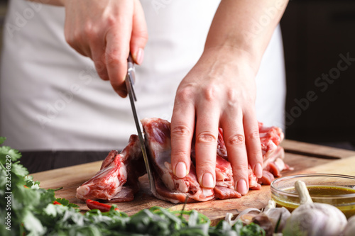 Female hands with a knife in their hand cut fresh meat on a table