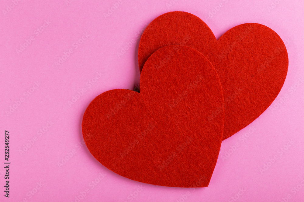 Two red felt heart on bright pink background