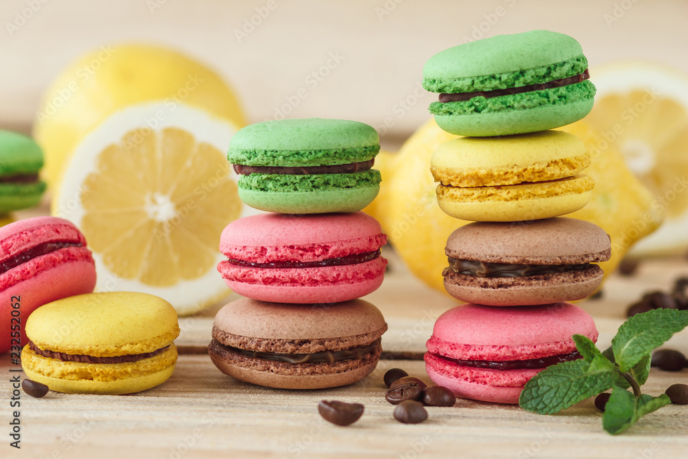Green, pink, yellow and brown french macarons with lemon and coffee beans