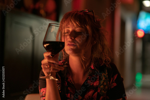 Beautiful ginger girl drinking a glass of red wine near a fire pit