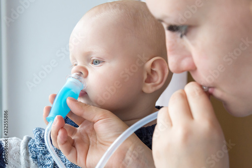 Mom cleans baby's nose using a nasal aspirator