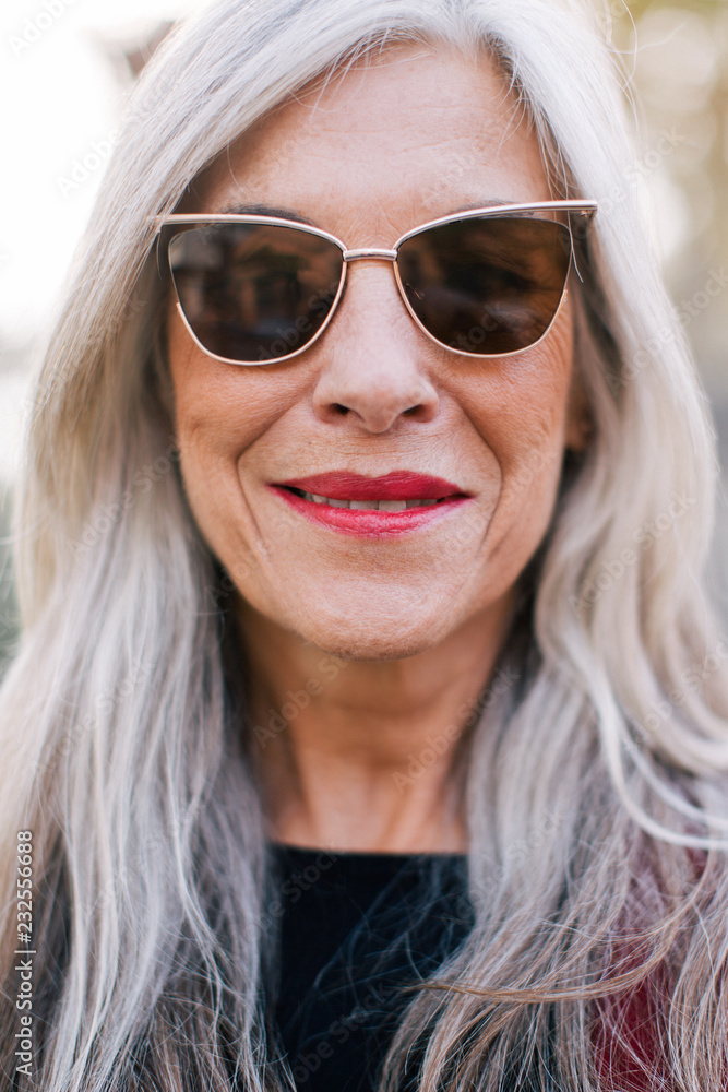 Closeup portrait of a mature woman with grey hair wearing sunglasses. Closeup portrait of a mature woman with grey hair wearing sunglasses.