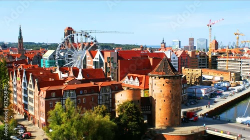 Gdansk, Poland. Sunny day view of Brama Stagiewna and other historical buildings in Gdansk, Poland. Car traffic trail with clear blue sky. Ferris Wheel and construction site photo