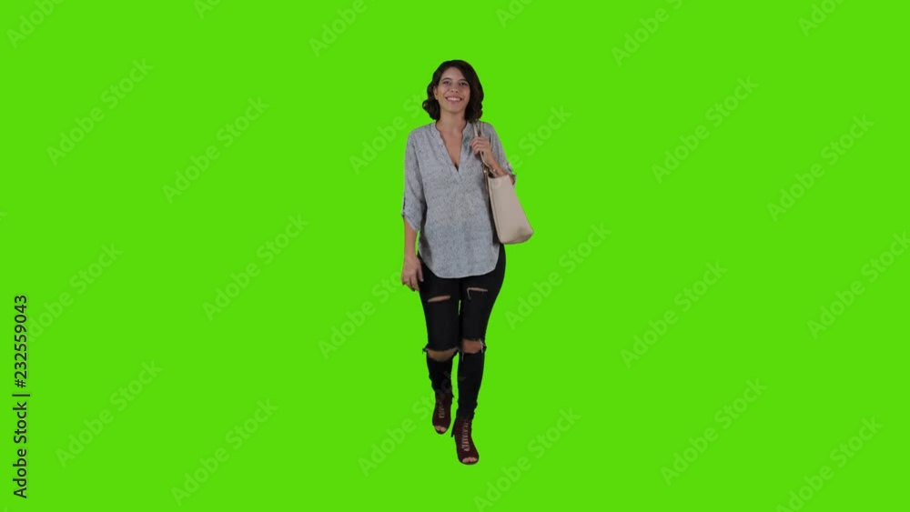 Young woman, casual look, walking smiling and waving hello in a full frontal body shot over a green screen. Young woman, casual look, walking smiling and waving hello in a full frontal body shot over a green screen.