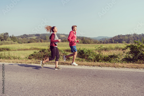 young couple jogging along a country road