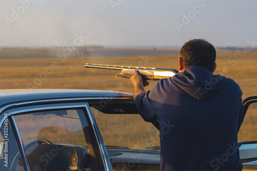 The guy shoots cartridges with a gun in nature, The hunter shoots at the target at sunset 