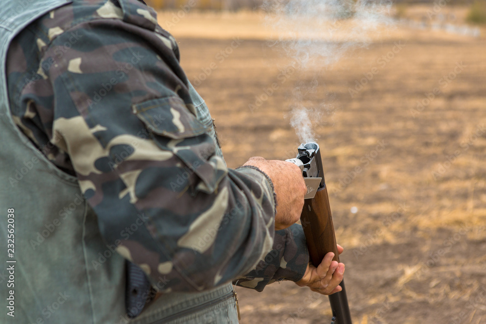 Fototapeta premium The hunter reloads the weapon, the smoke from the gun barrels