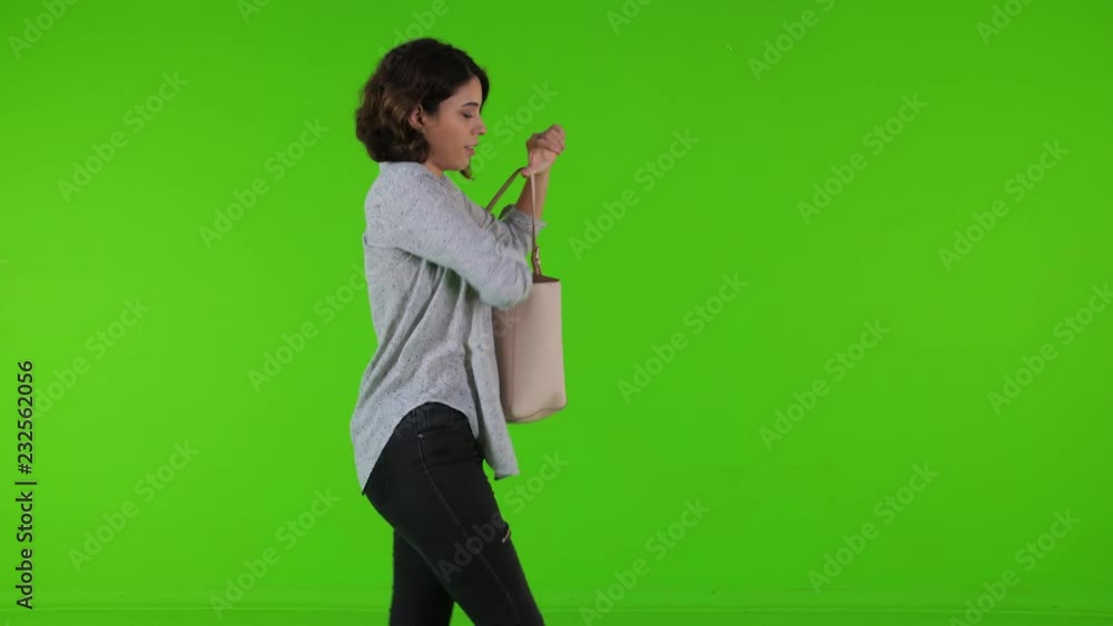 using an app or texting happily while walking by a young woman over a green screen. casual look medium side shot. using an app or texting happily while walking by a young woman over a green screen. casual look medium side shot.