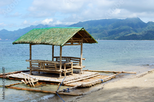 Floating beach bamboo and palm cottage parasol on white sand coast