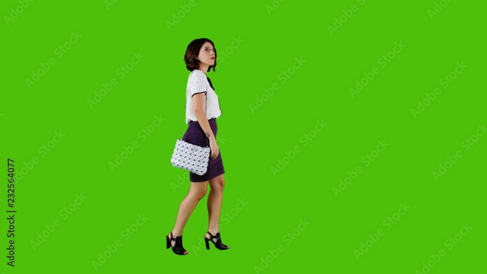 Stylish woman walking casually over a green screen in a full side shot. Stylish woman walking casually over a green screen in a full side shot.