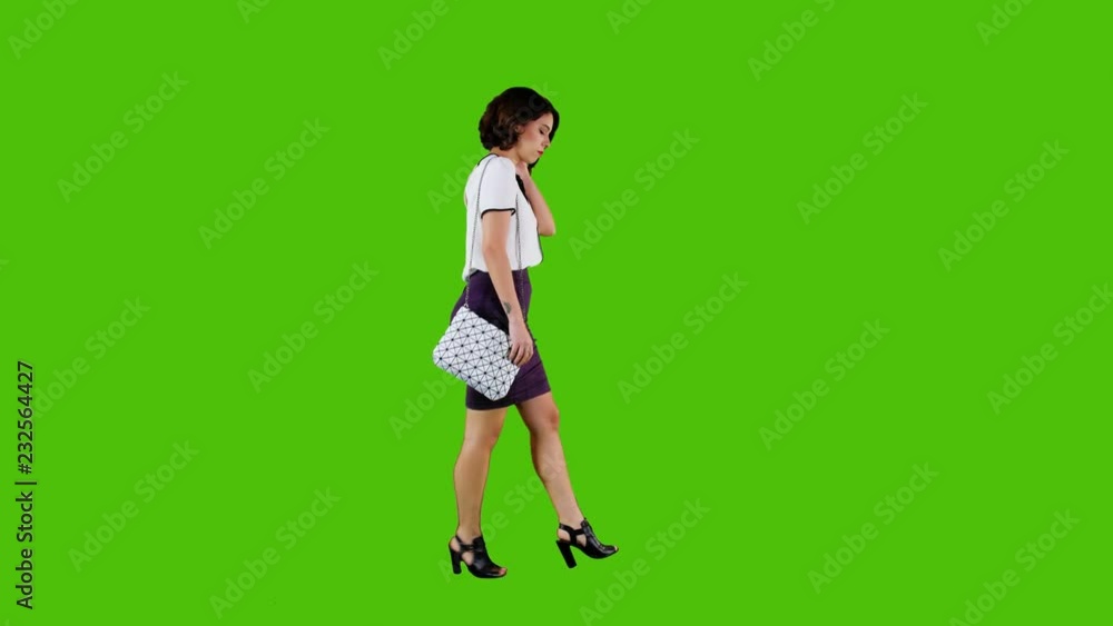 Stylish sad woman walking while having a headache over a green screen in a full side shot. Stylish sad woman walking while having a headache over a green screen in a full side shot.