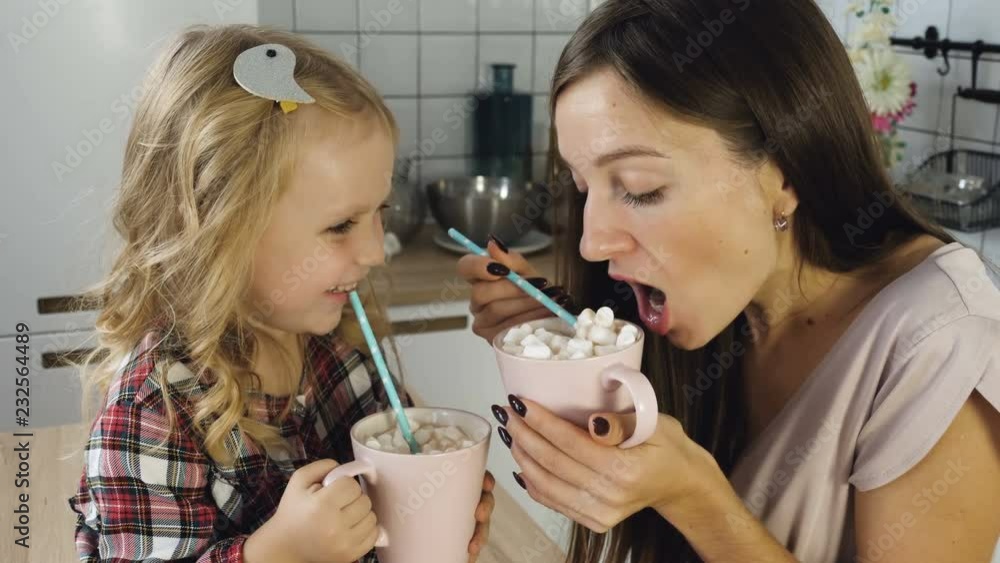 Mother and daughter drink cocoa with marshmallow Mother and daughter drink cocoa with marshmallow