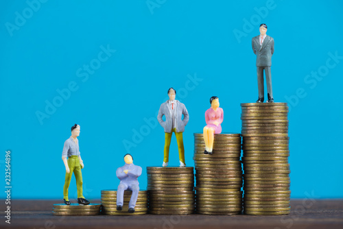 Figure miniature businessman or small people investor and office worker secretary standing on coin stack, for money and financial business success concept.