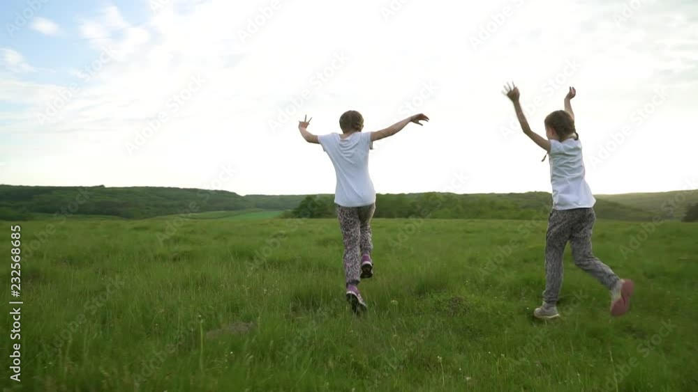 Two sisters running and having fun in meadow Two sisters running and having fun in meadow
