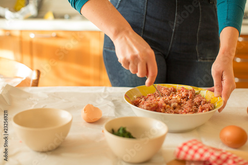 Woman mixing meat rolled roast with a boiled egg and spinach filling photo