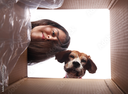 Happy teen girl and her dog looking at something inside a box