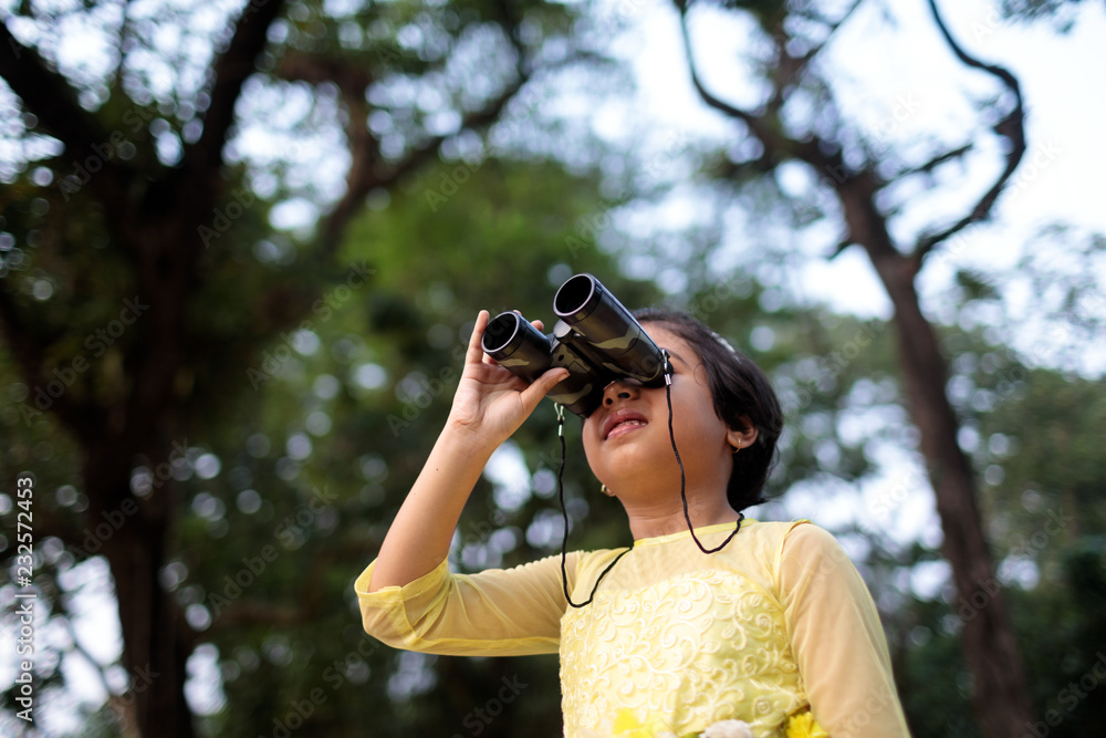 Little girl looking through a binocular in the forest Little girl looking through a binocular in the forest