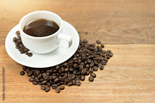 Hot Coffee cup with coffee beans with copy space on wooden table.