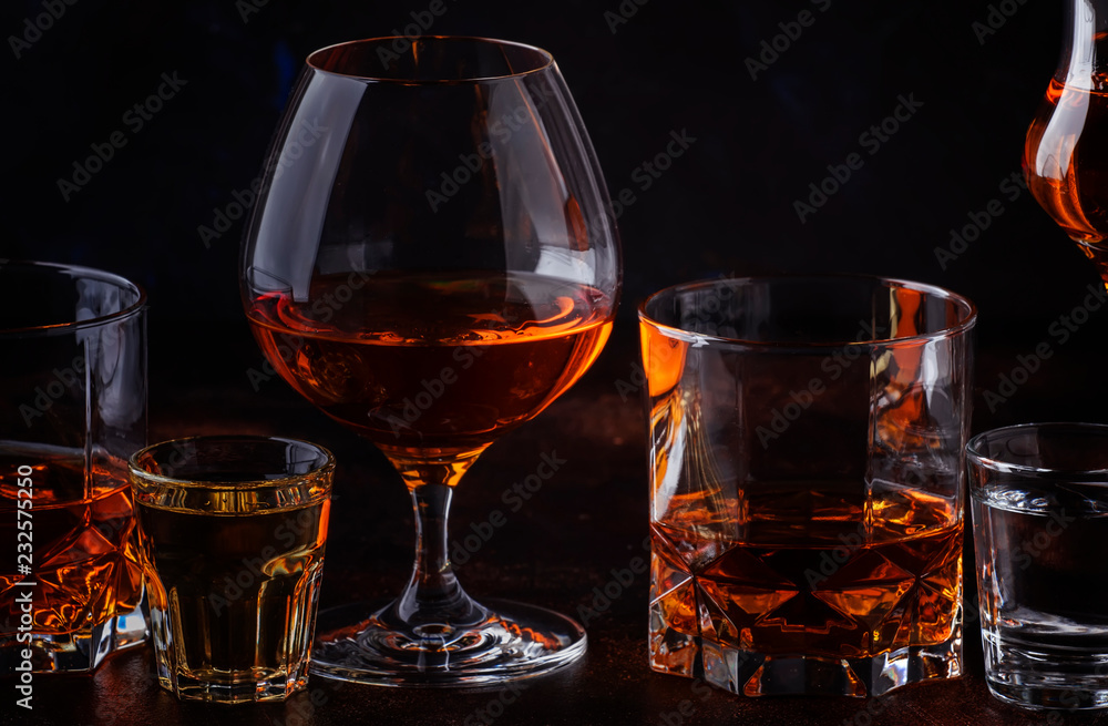 Set of strong alcoholic drinks in glasses and shot glass in assortent: vodka, rum, cognac, tequila, brandy and whiskey. Dark vintage background, selective focus Set of strong alcoholic drinks in glasses and shot glass in assortent: vodka, rum, cognac, tequila, brandy and whiskey. Dark vintage background, selective focus