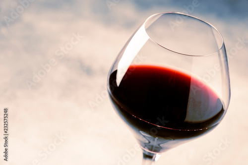 Red wine from grape varieties merlot in glass, gray table, selective focus, shallow DOF photo