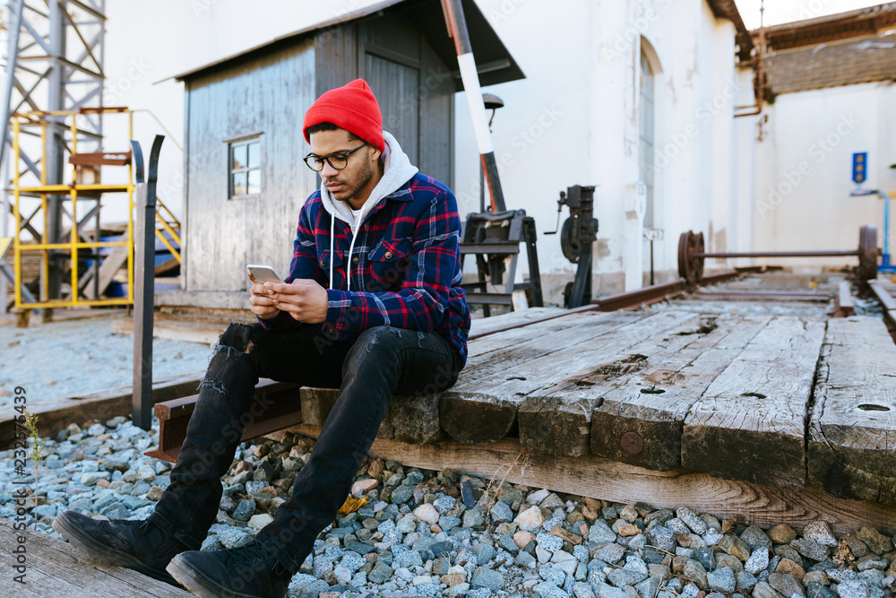 Young traveler using phone waiting in a train station. Young traveler using phone waiting in a train station.