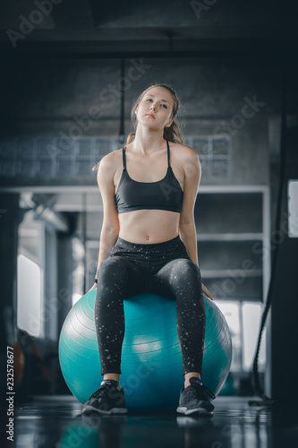 Young attractive woman fitness doing exercises workout on ball in gym. Woman stretching the muscles and relaxing after exercise at fitness gym club. photo