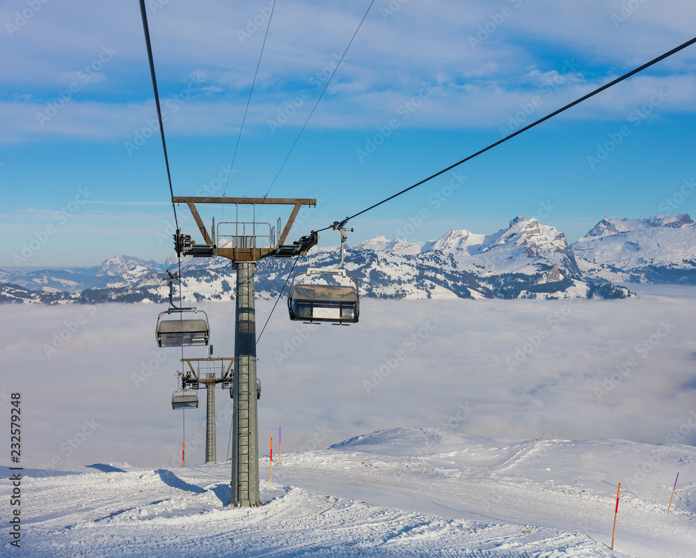 An overhead cable car, summits of the Alps rising from sea of fog - a wintertime view from the Fronalpstock mountain in the Swiss canton of Schwyz An overhead cable car, summits of the Alps rising from sea of fog - a wintertime view from the Fronalpstock mountain in the Swiss canton of Schwyz