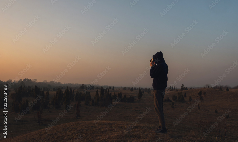 Look from behind on man standing in front of wasteland with camera Look from behind on man standing in front of wasteland with camera