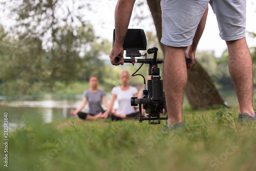 young videographer recording while woman doing yoga exercise