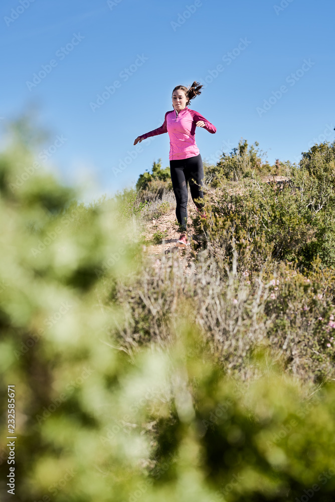 Sportive woman running downhill in nature Sportive woman running downhill in nature